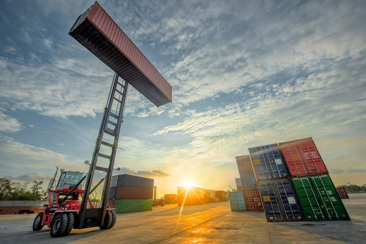 Stacker forklift lifting a unit of containers in a container yard
