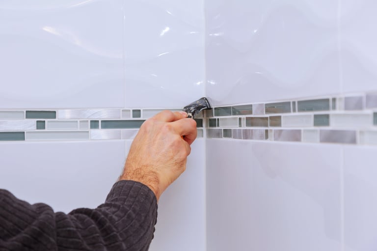 Home improvement renovation applying silicone sealant with construction worker fills seam on ceramic tiles in bathroom