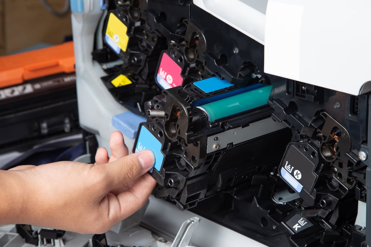 Technician checking and replacing the toner cartridges of a laser multifunction printer in the office