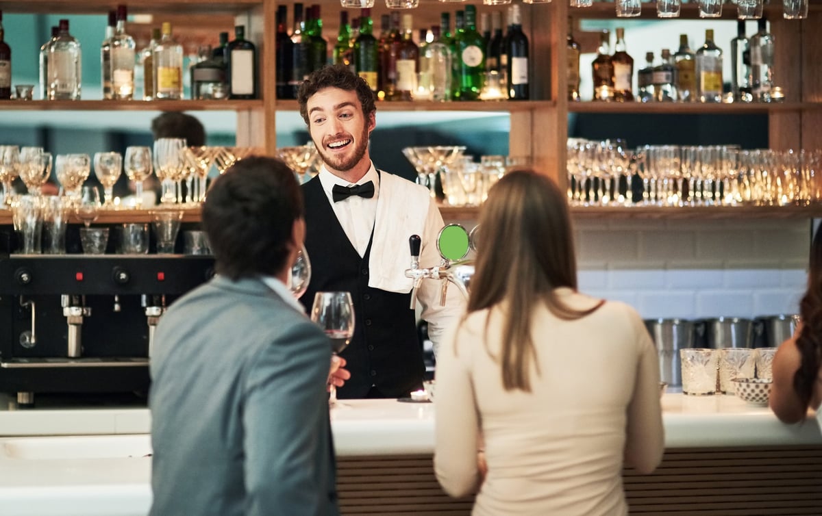 Cropped shot of a handsome young barman serving a young couple in a bar