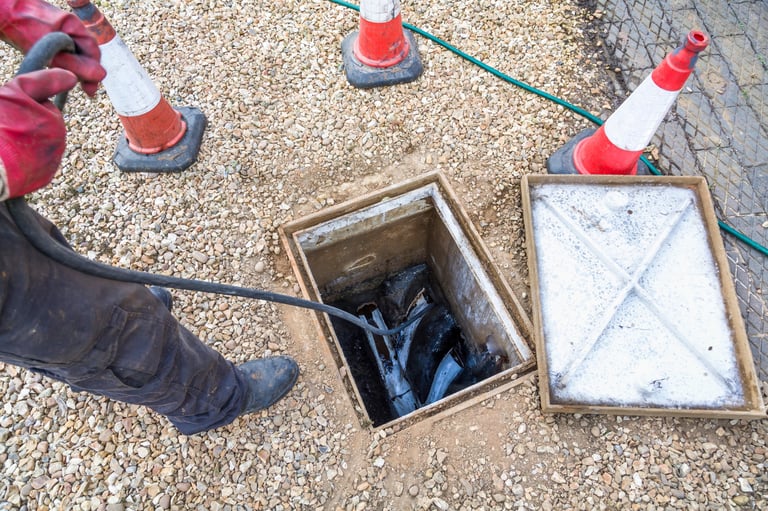 Drainage professional unblocking domestic sewage drain through open inspection chamber