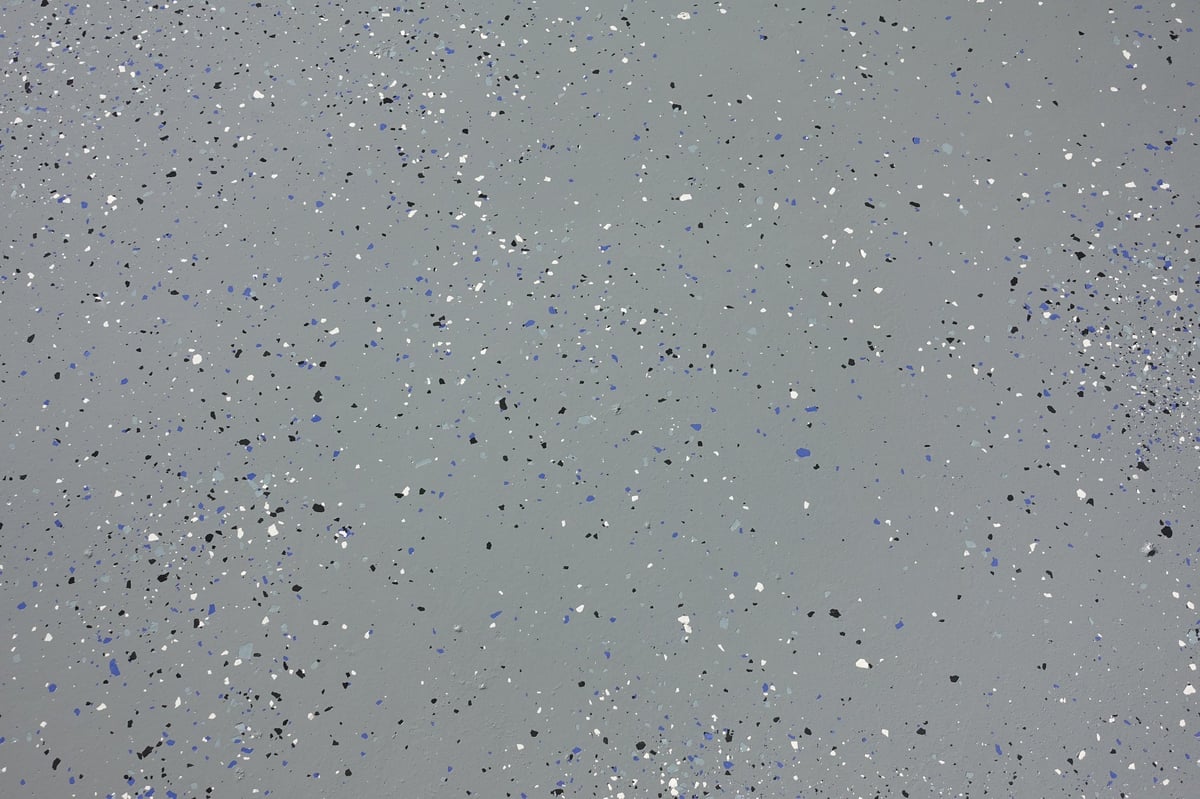 Full-flake epoxy floor fresh install — gray base with blue, black, and white chips fully broadcast