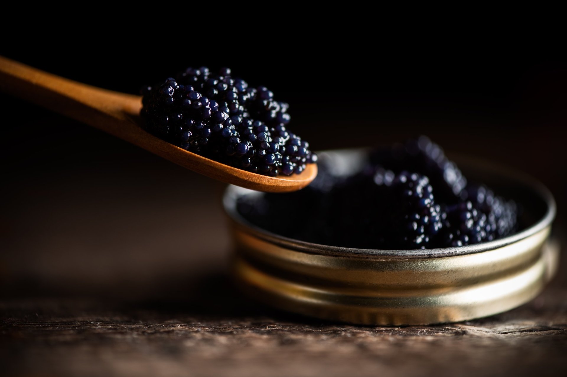 Black lumpfish caviar in a small pot and spoon, served in classic caviar tradition