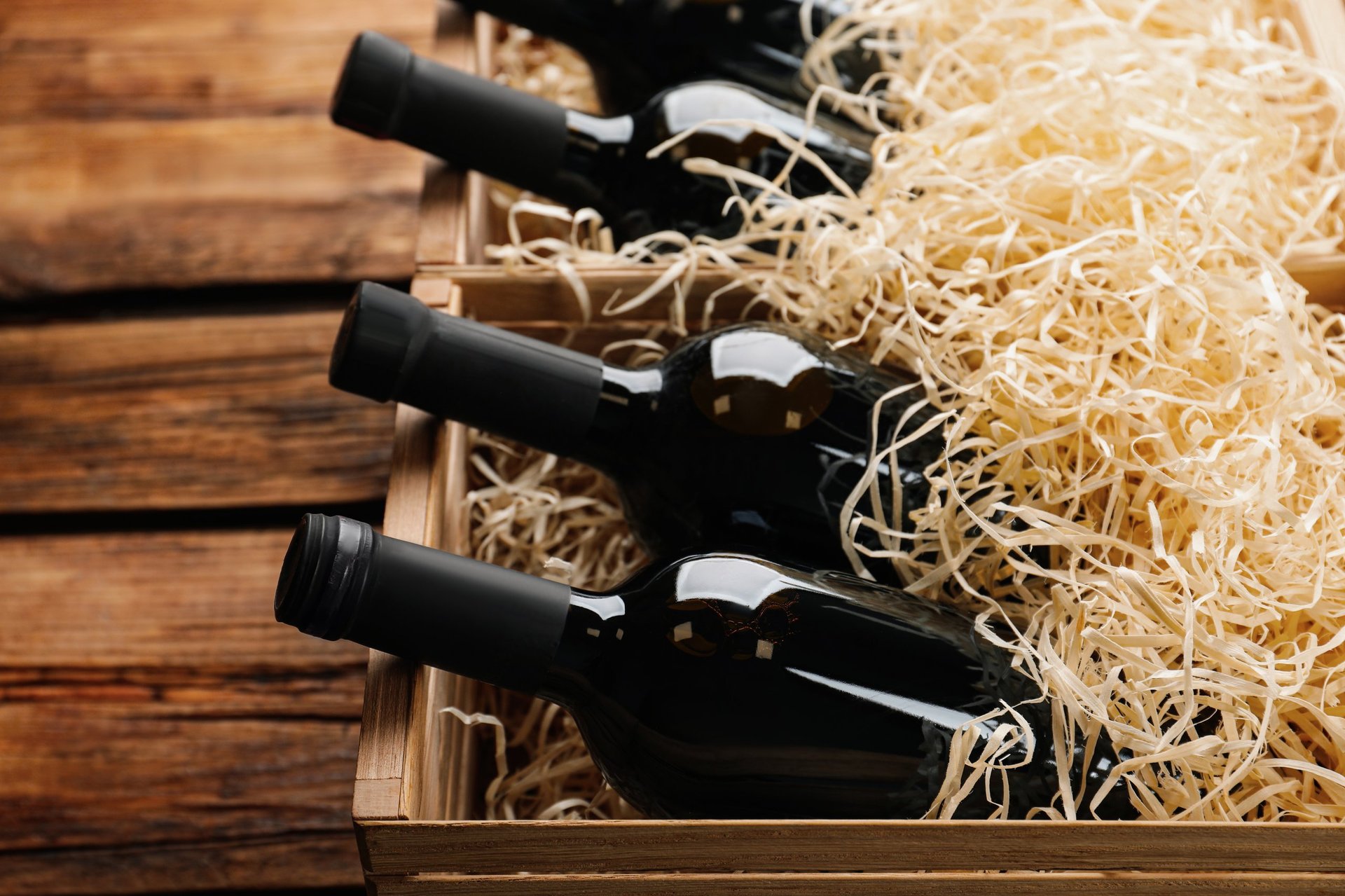 Crates with bottles of wine on wooden background
