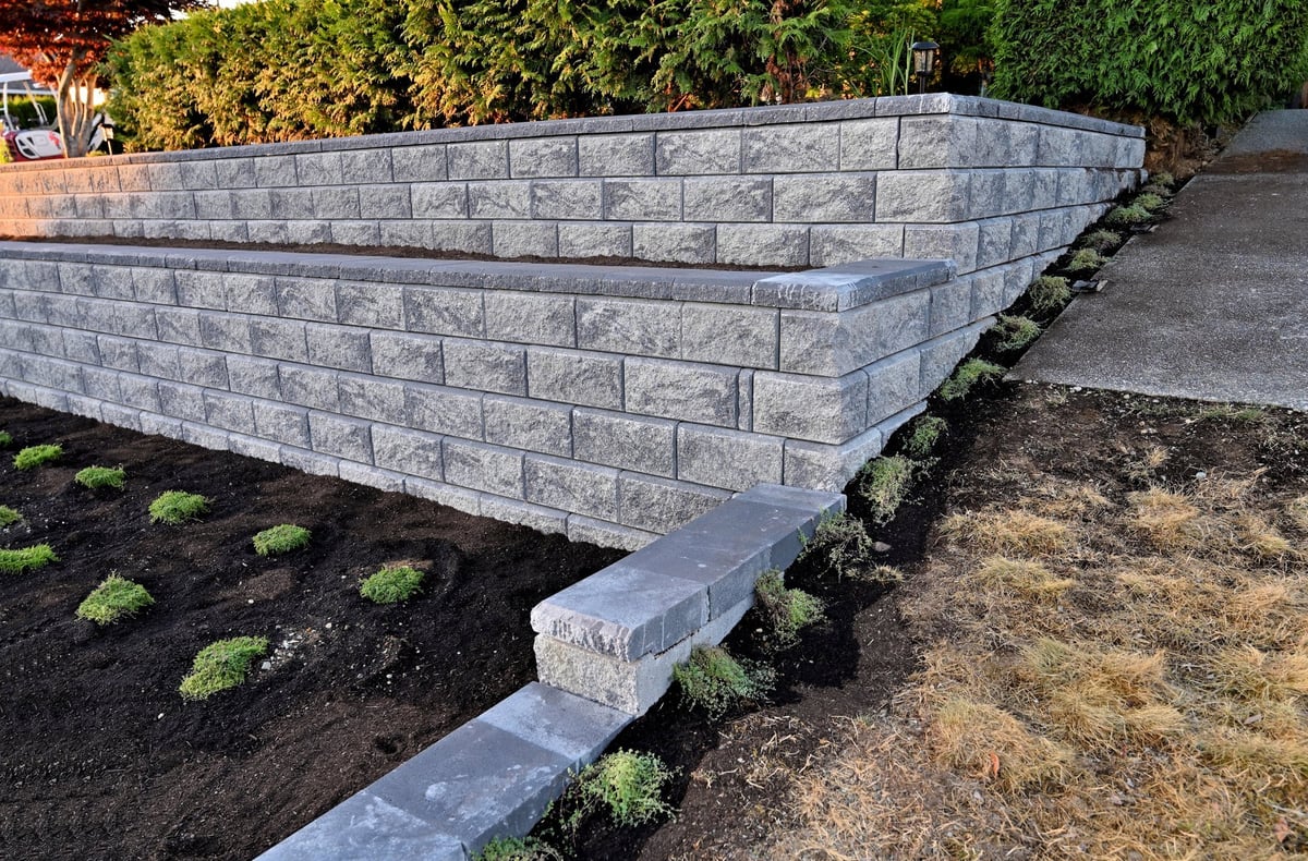 Side view of a staggered two-tier retaining wall in gray, a beautiful hardscape design in the front yard