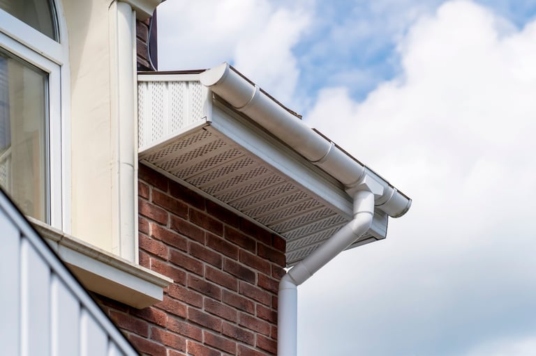 Close-up of gutter system with soffit vent and decorative trim on brick house