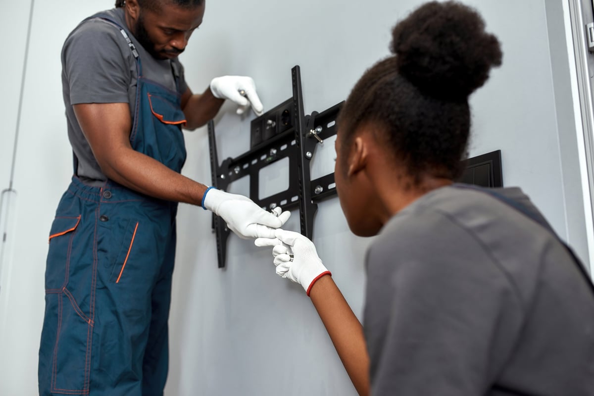 Professional TV mounting team installing a bracket on a wall