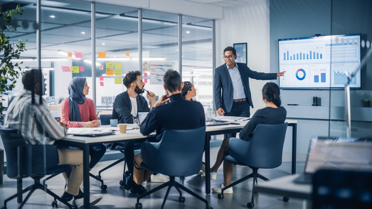 Presentation in Multi-Ethnic Office Conference Room. Meeting of Diverse Young Entrepreneurs, Specialists, Talking, Using TV for infographics.