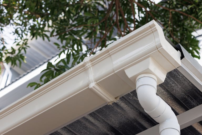 White vinyl rain gutter and downspout on a house