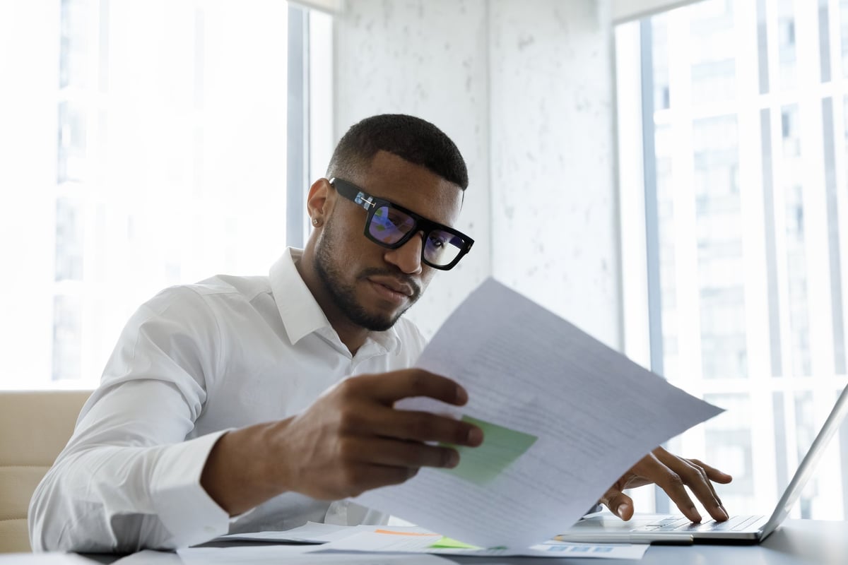 Business owner in glasses reviewing sales reports and financial documents