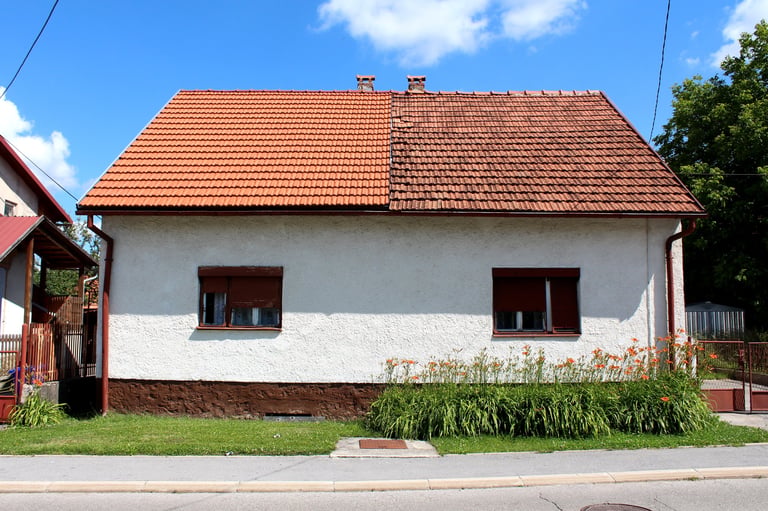 Split suburban house — left side with new red roof tiles, right side with old dilapidated roof tiles showing dramatic roof restoration difference