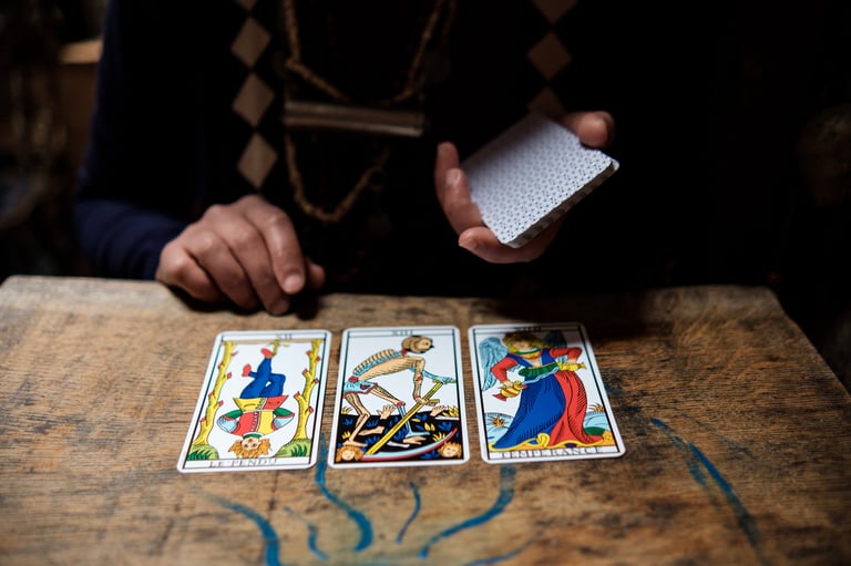 Tarot cards and the hand of a reader spread on a wooden table in candlelight