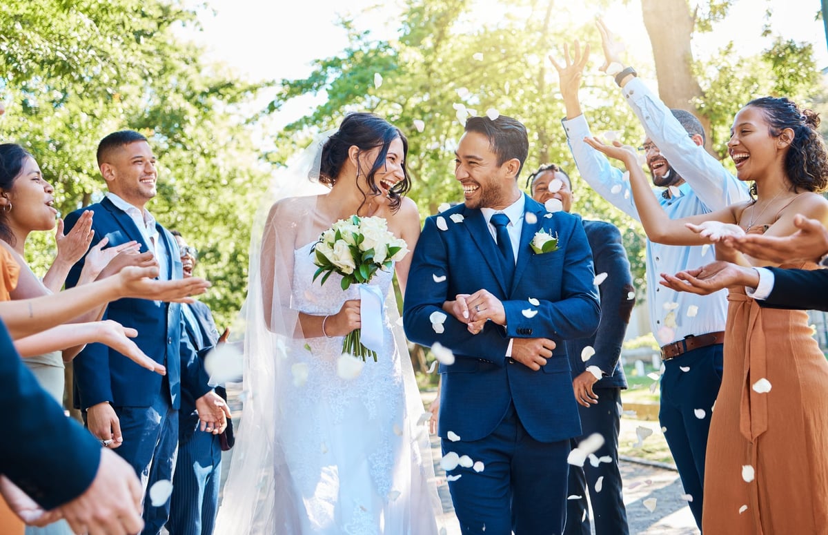 Wedding guests throwing rose petals confetti over bride and groom celebrating their special day