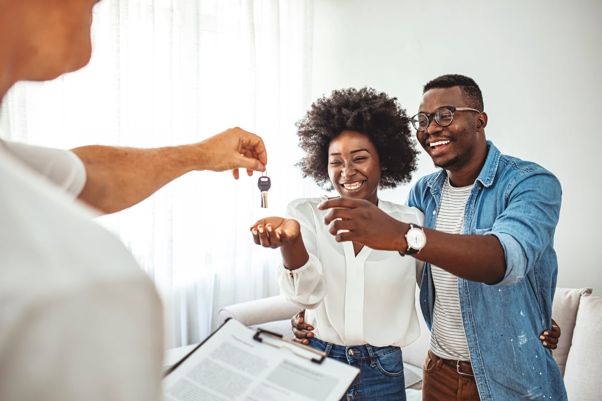 Real estate agent handing the keys of a new home to a young couple