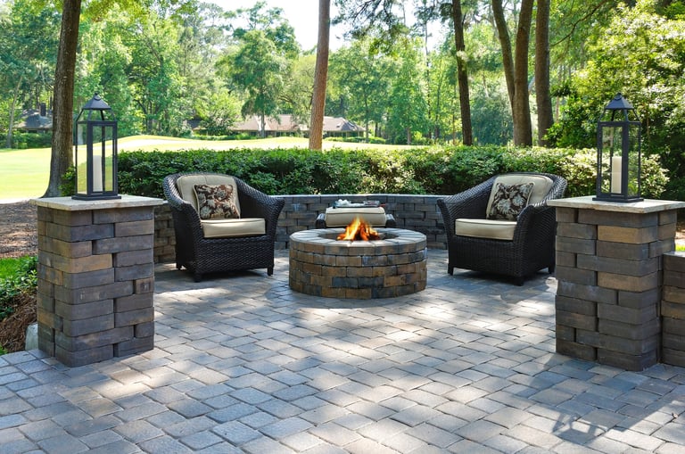 Beautiful paver patio with two armchairs and a fire pit in a natural green setting