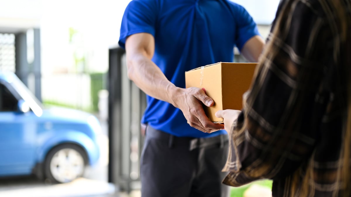 Repartidor de Lulos Pack entregando paquete a cliente junto a su van