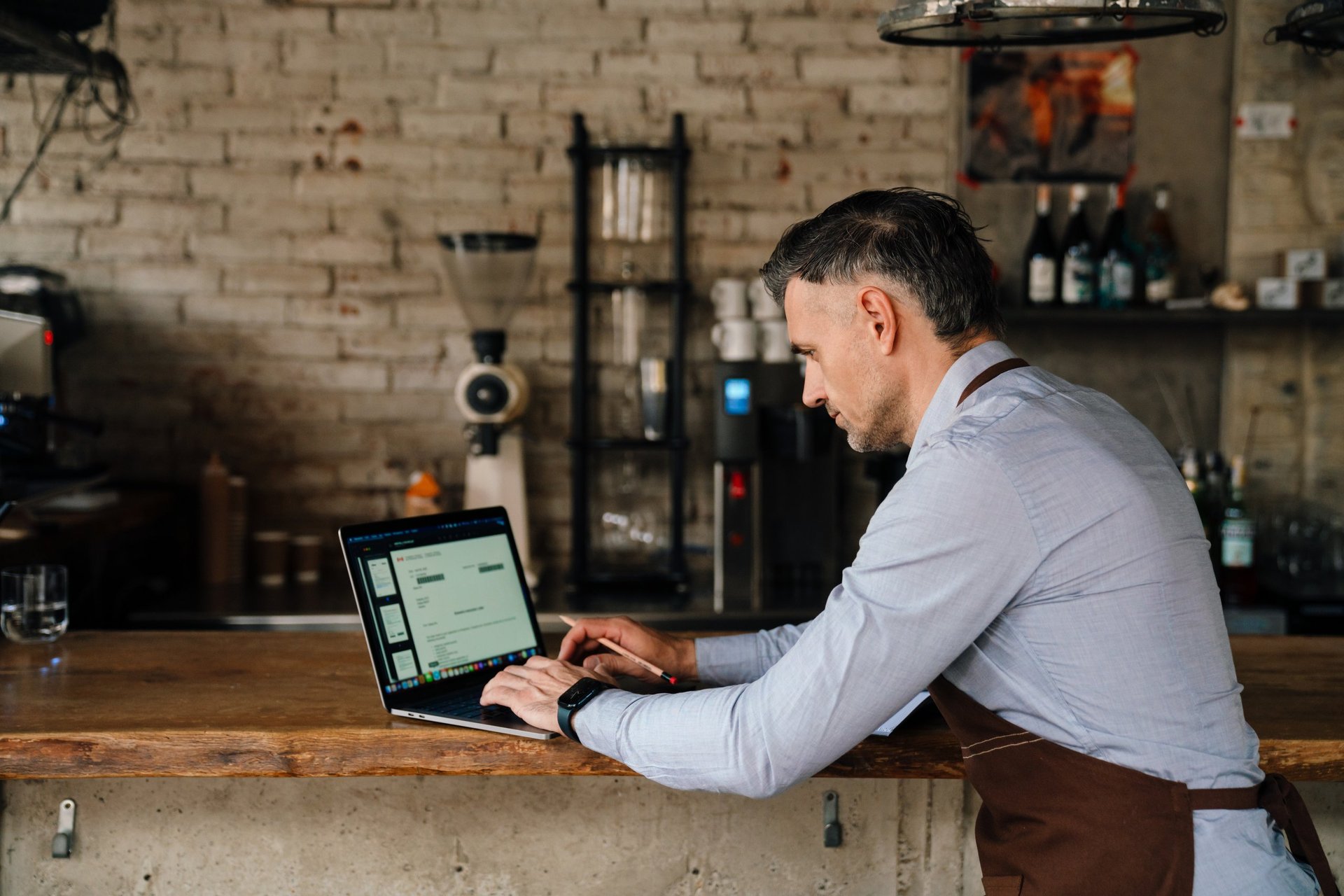 A café owner working on a laptop at the counter of their business