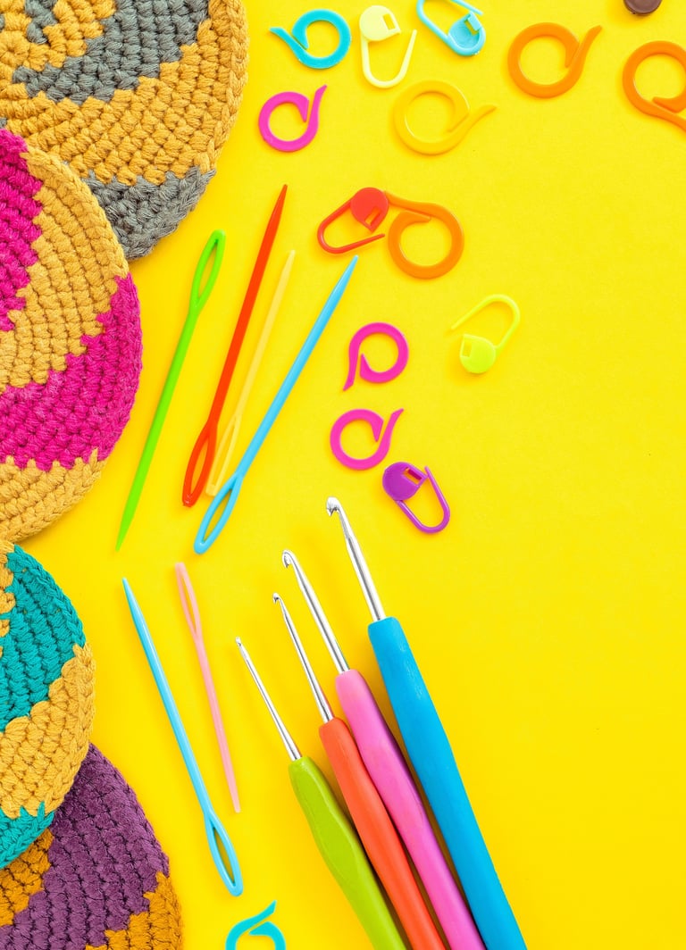 Crochet cup coasters and knitting tools on a yellow background with crochet hooks, markers and needles