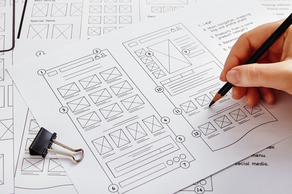 UX designer working on website project with wireframe sketches spread across the desk