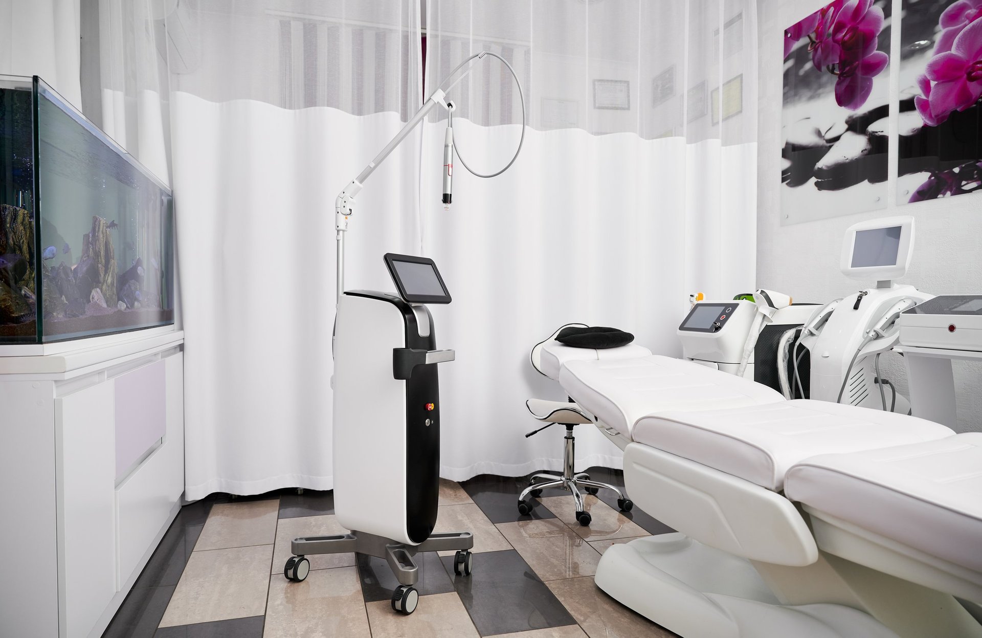 A treatment room with modern skincare and laser equipment and a salon chair