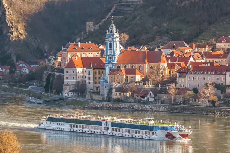 River cruise ship on the Danube through Wachau, Austria with historic village architecture
