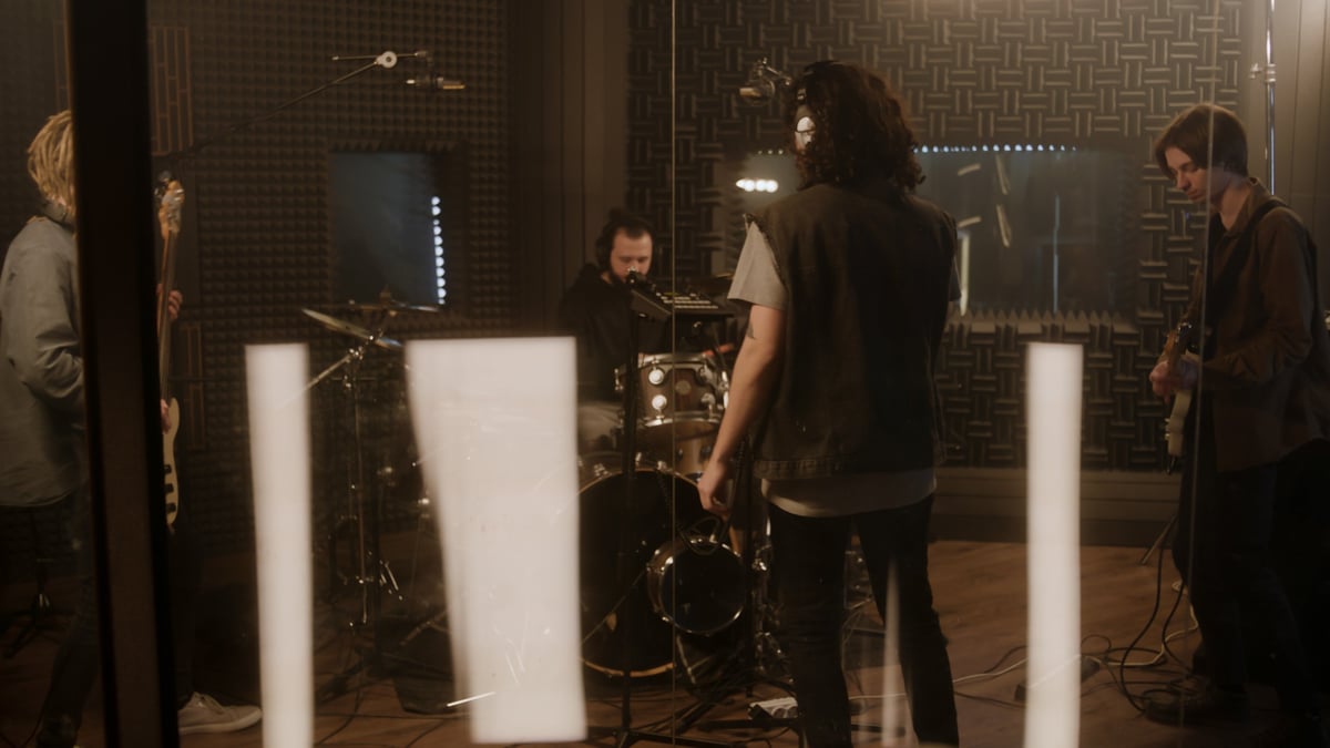 Cool rock band recording in soundproof studio with professional equipment