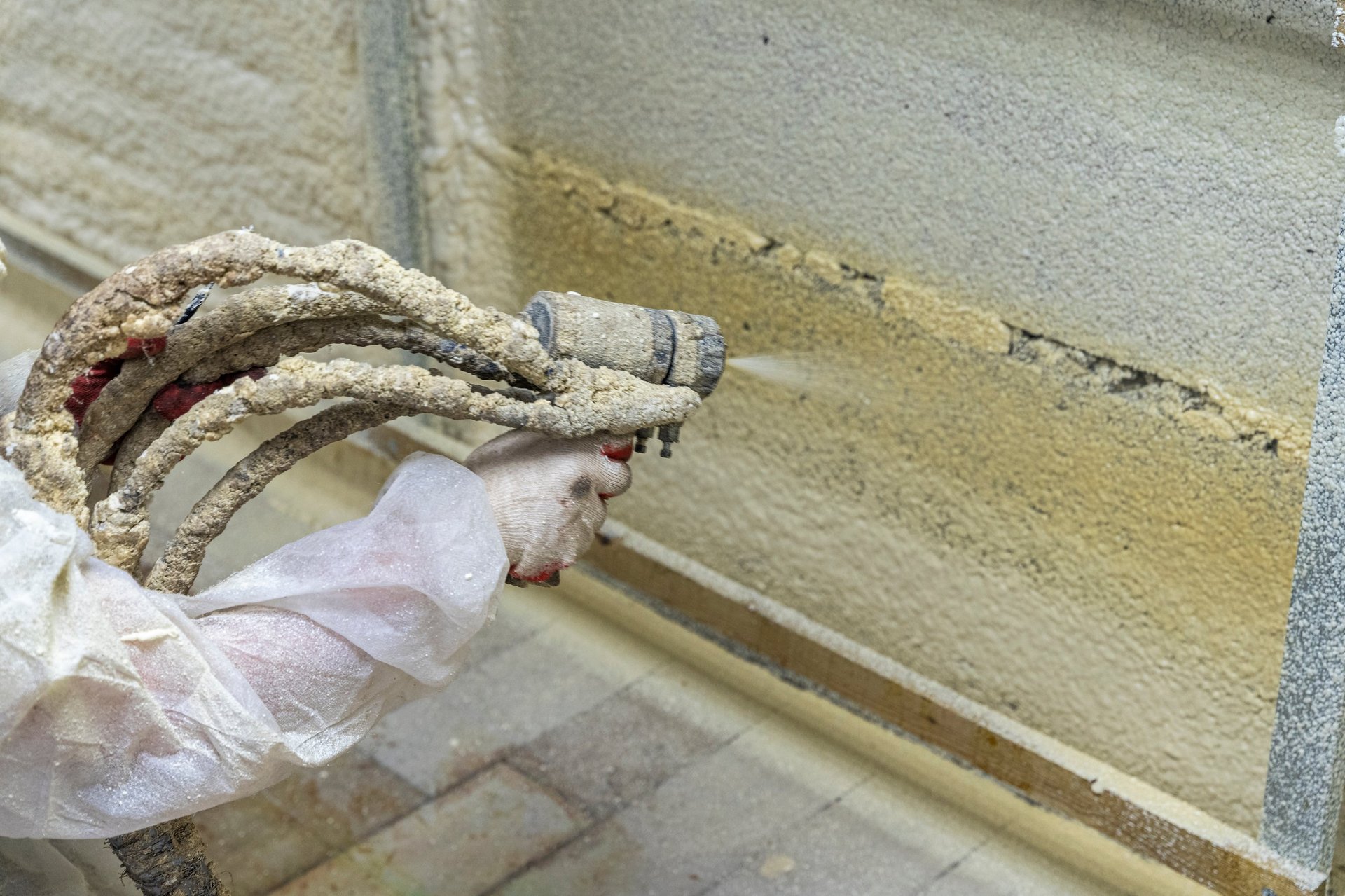 Builder insulating wooden frame house by spraying polyurethane foam