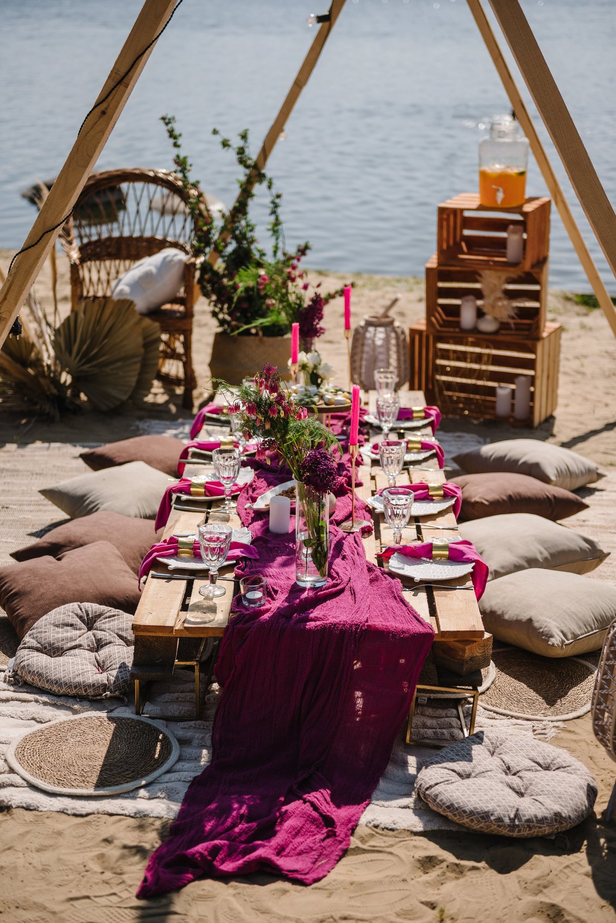 Elegant boho-style picnic with a floral arch, pillows, blankets, garlands, and romantic pastel decor