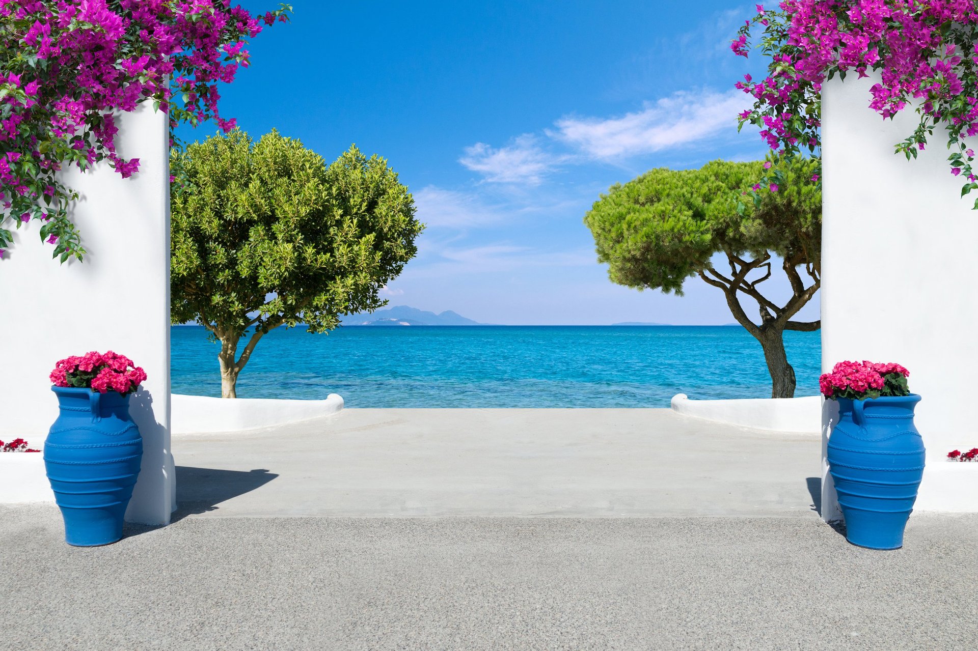 Elegant white Mediterranean terrace with bougainvillea overlooking vivid blue sea and distant island under a bright blue sky