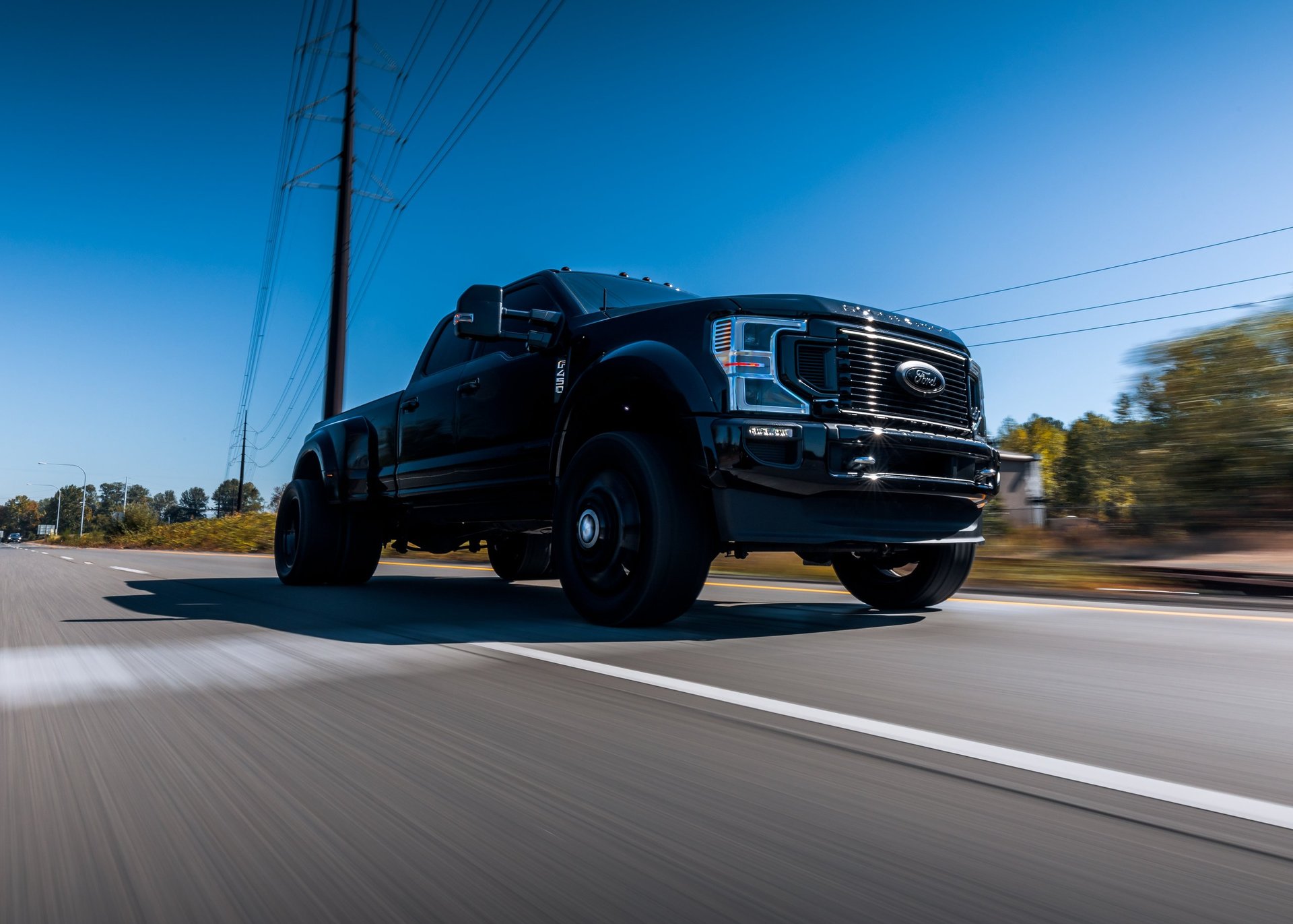 A black Ford F450 commercial truck driving on the highway