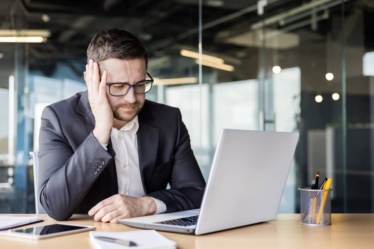 Upset person at a desk with a laptop, frustrated by a website experience