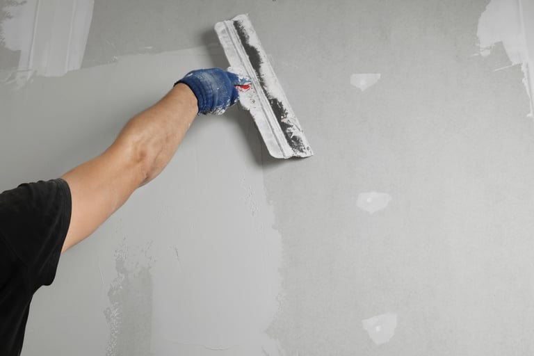 Professional worker plastering wall with putty knife