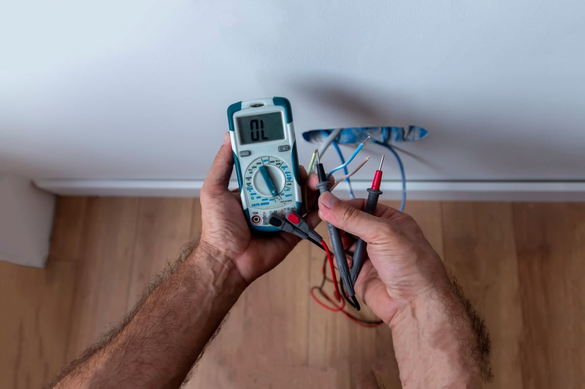 Fachmann misst die Spannung an einer Steckdose mit einem digitalen Multimeter – professioneller E-Check