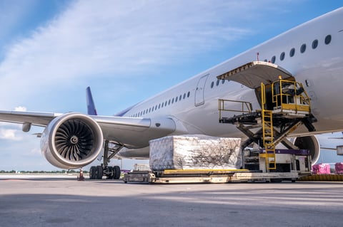 Avión de carga con contenedores logísticos siendo cargados en aeropuerto