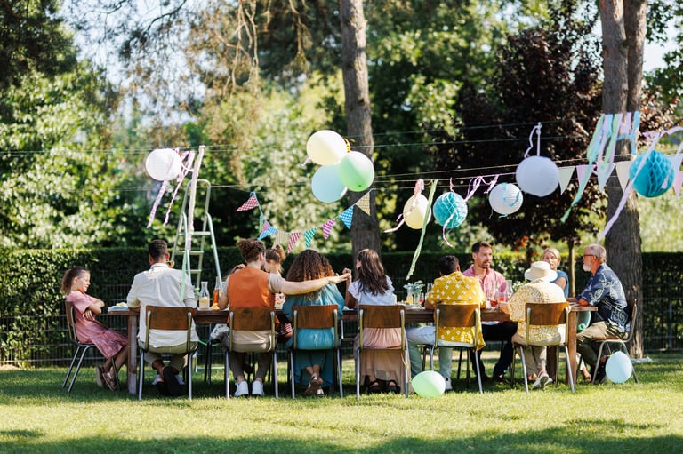 Family and friends sitting at the party table during a summer garden party outdoors