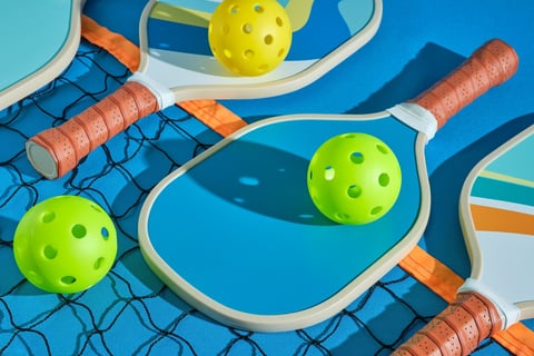Pickleball paddles and balls on a professional net