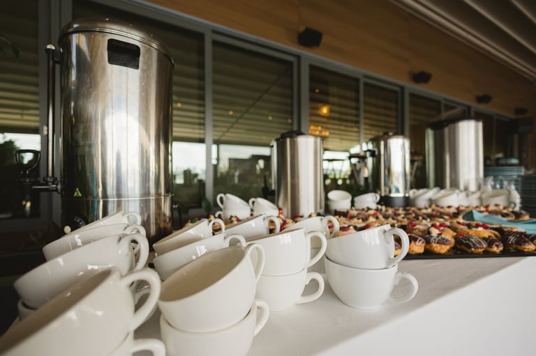 Coffee cups lined up on a conference catering table