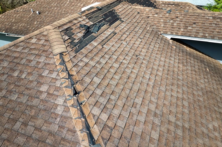 Wind damaged house roof with missing asphalt shingles after hurricane Ian in Florida. Repair of home rooftop concept.