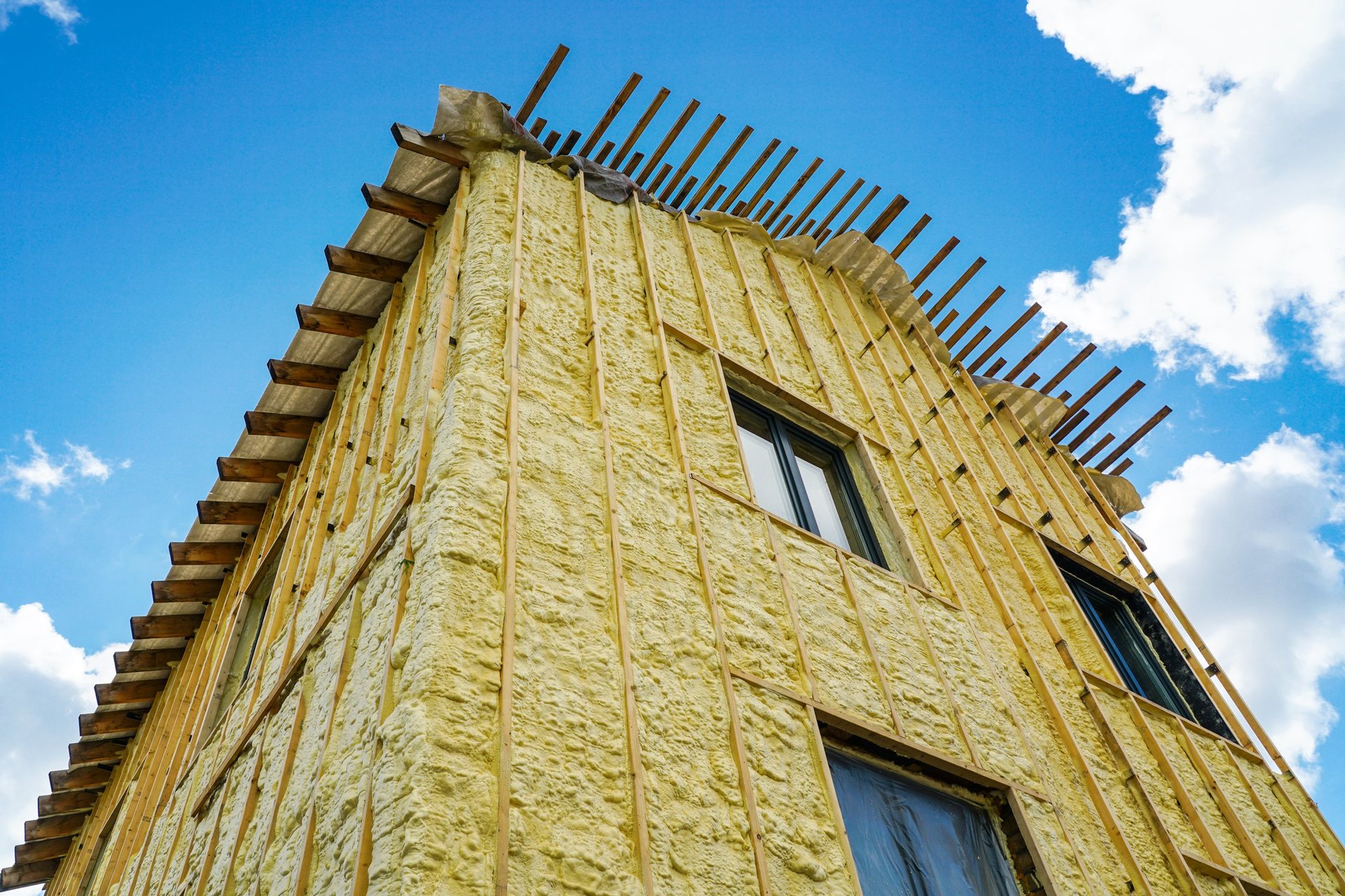 Builder insulating wooden frame house by spraying polyurethane foam