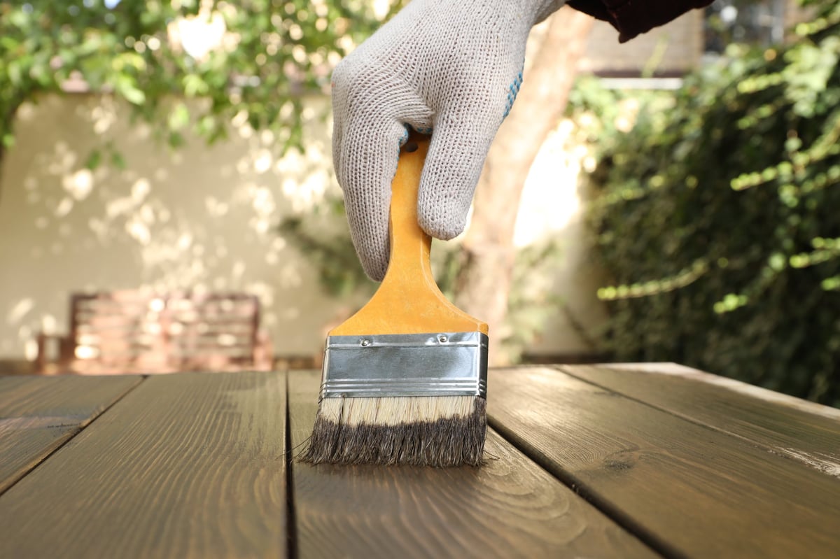 Professional applying wood stain to a deck board, restoration work in progress