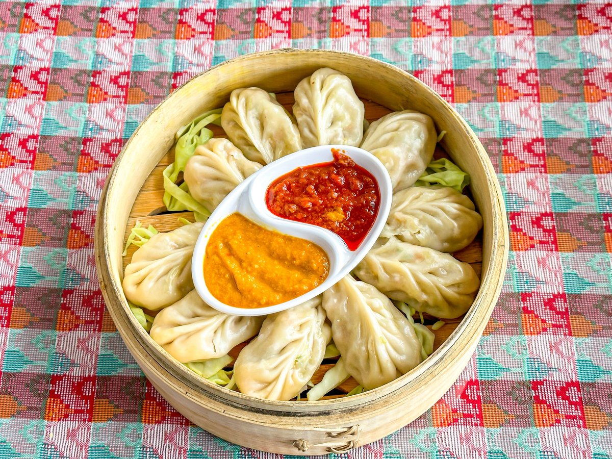 Close-up of beautifully plated momos with dipping sauce