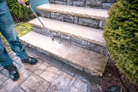 Man cleaning outdoor dirty porch stairs with a power wash machine