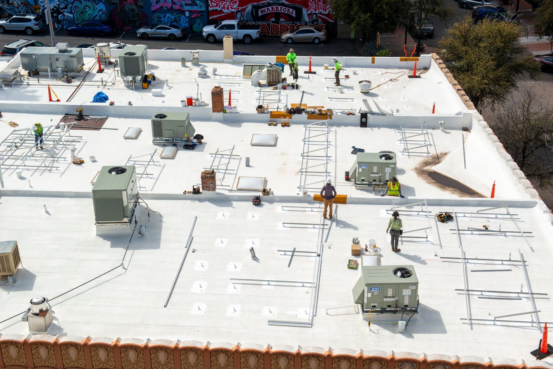 Workers on a commercial flat roof applying reflective roofing membrane