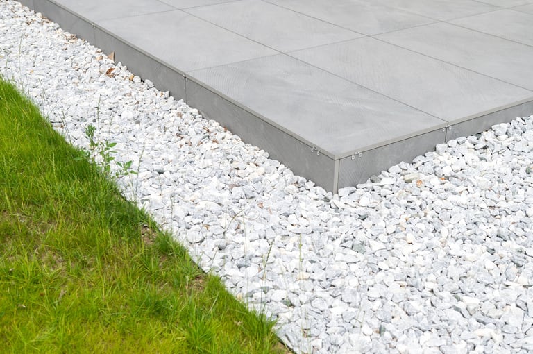 A modern staircase edge with contrasting grass and white pebbles