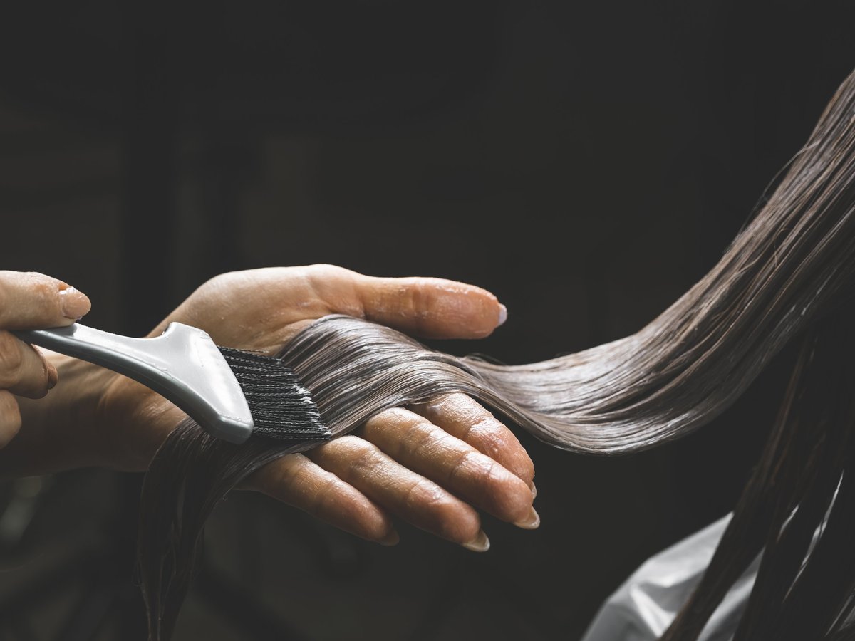 Colorist dyeing woman's hair with brush and foil