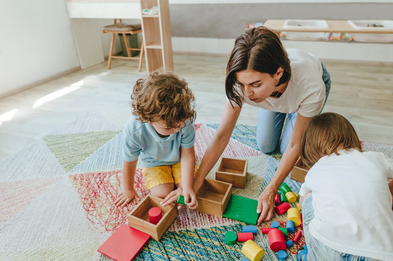 Young woman teacher playing with children on the floor with toys