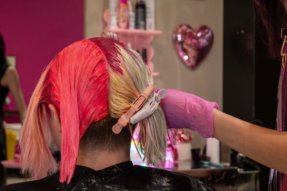 Woman getting her hair dyed pink at a salon