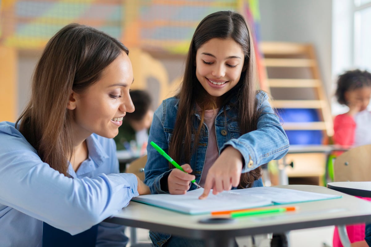 A Lighthouse teacher working one-on-one with a student at her desk