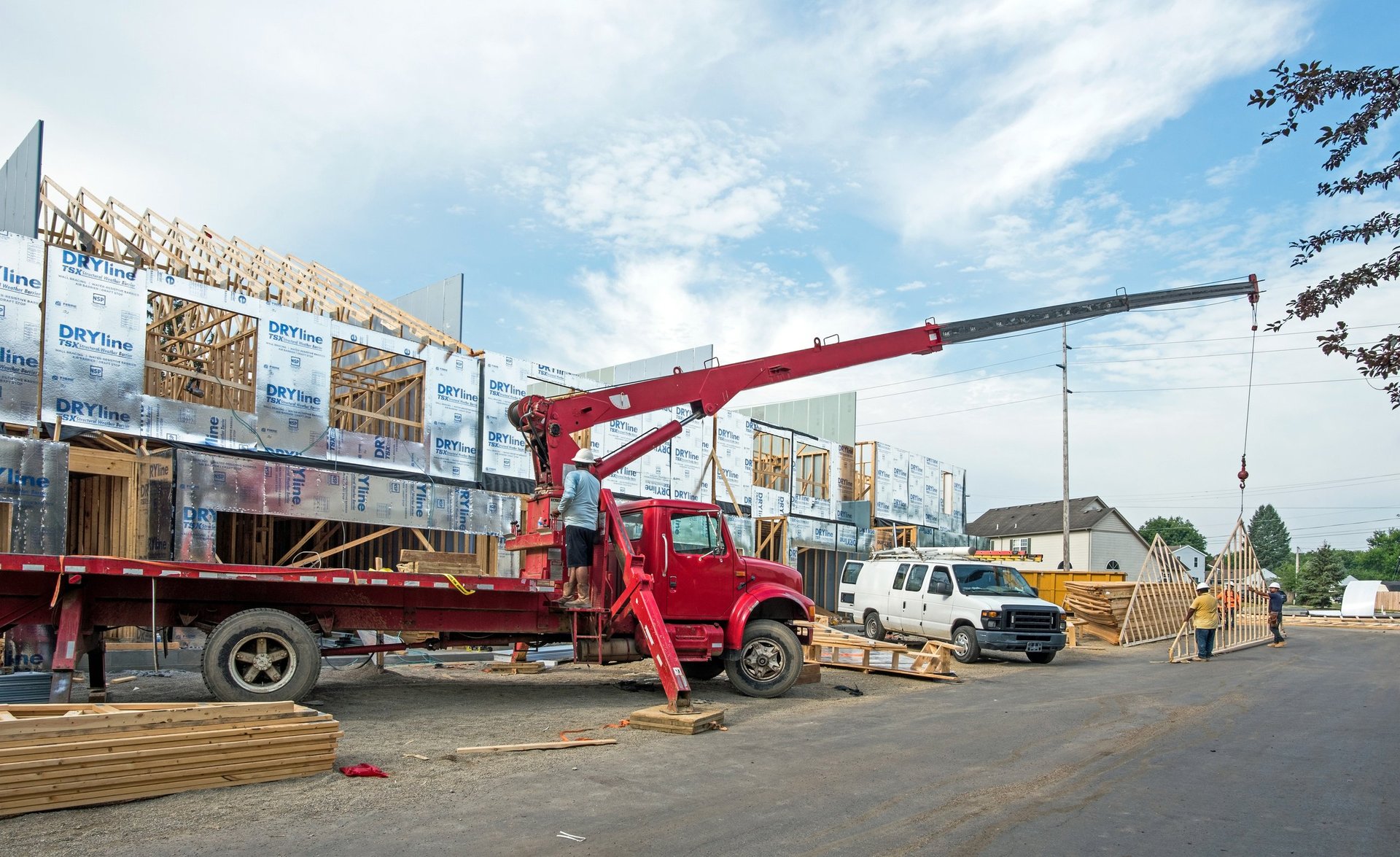 Construction workers steadying a roof rafter as a crane lifts it into place