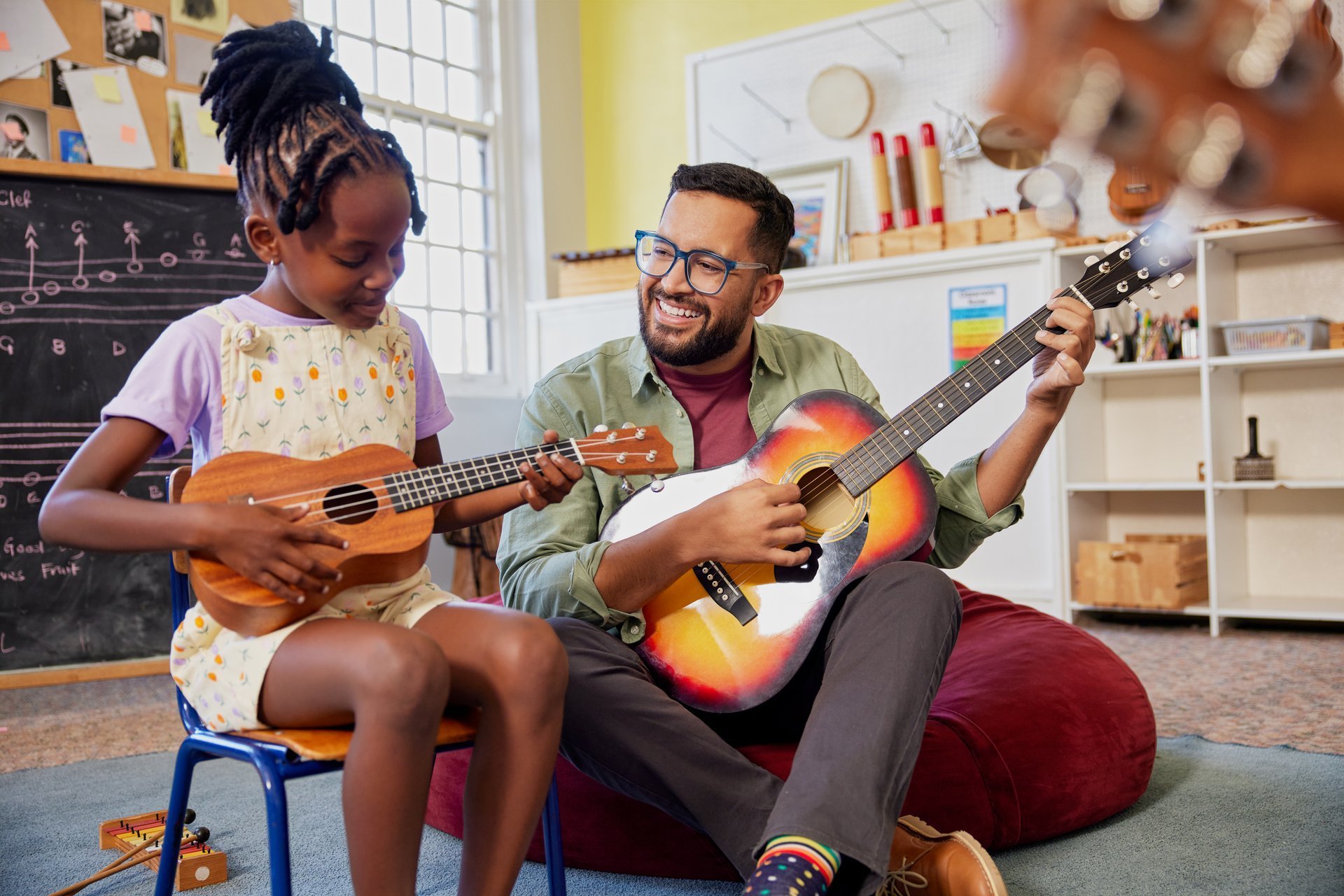 Teacher and children playing guitar and ukulele in music classroom